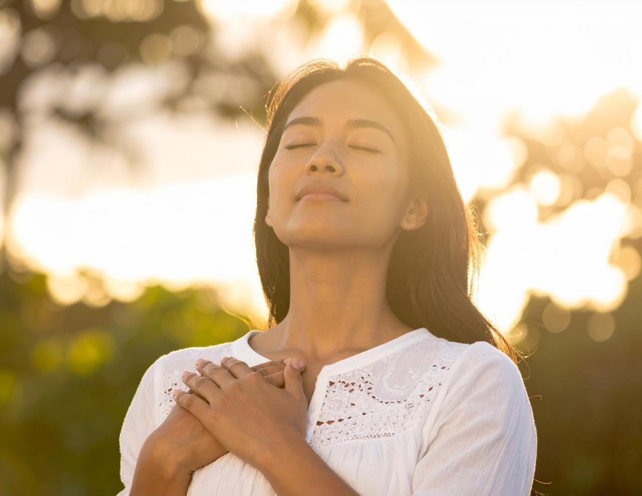 Hands on heart, eyes closed, golden light